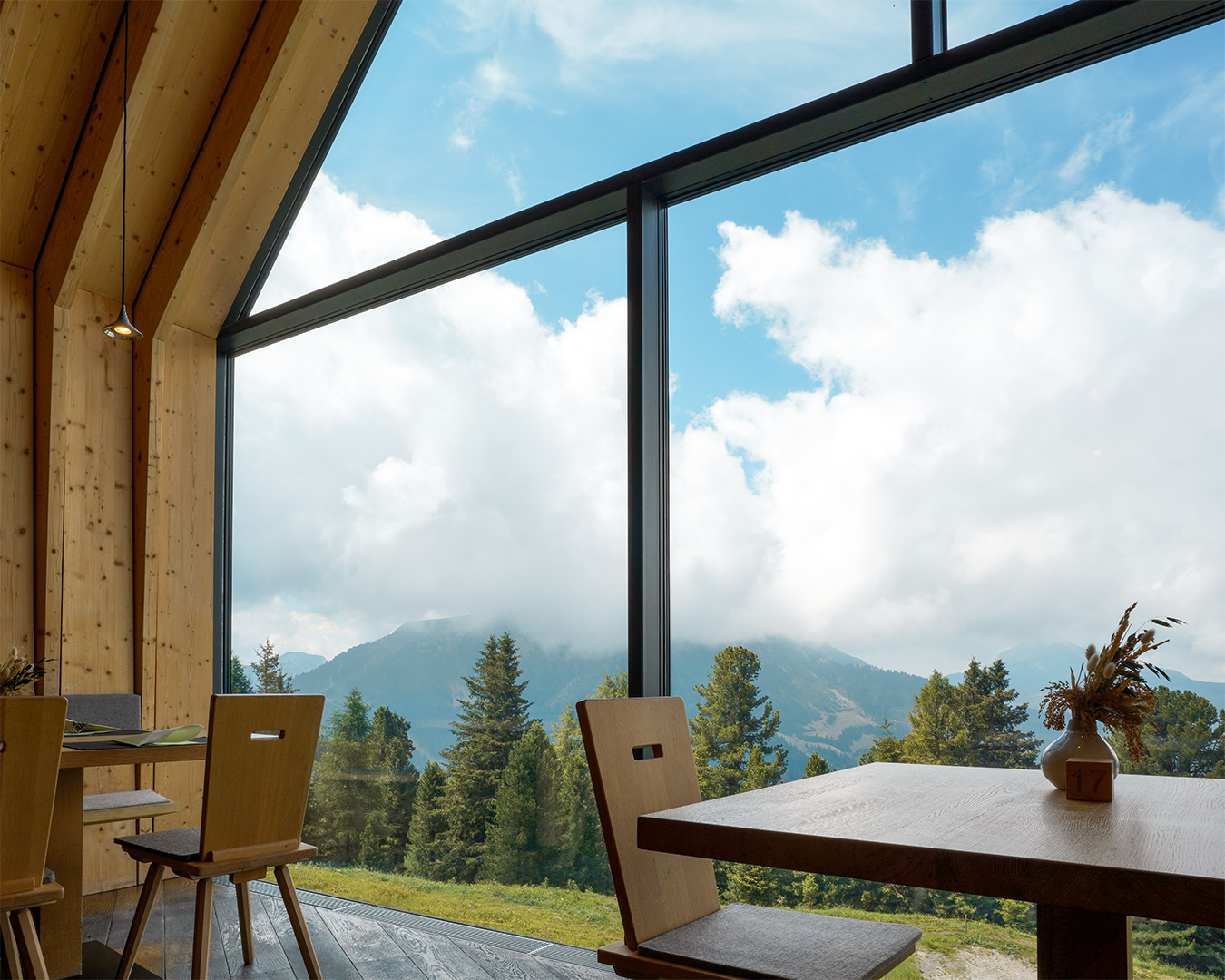 Vista del Rifugio Oberholz a Obereggen ai piedi del Latemar, edificio in legno che emerge dal pendio come un albero sdraiato