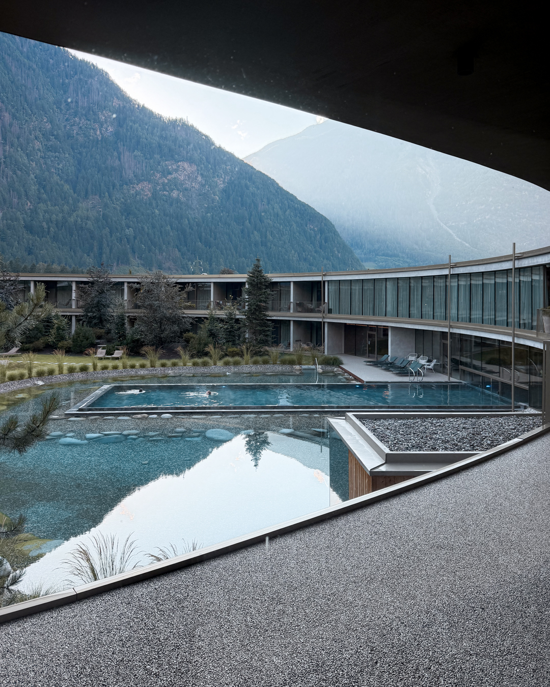 Involucro esterno con ampie superfici vetrate e calcestruzzo in architettura alpina contemporanea ad alte prestazioni energetiche